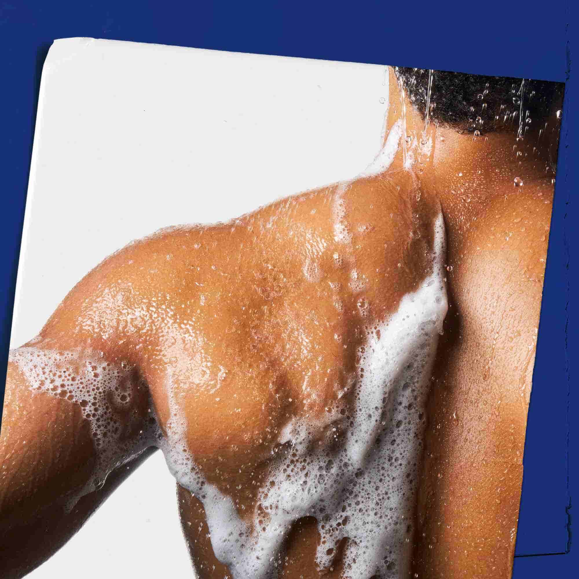 Nettoyant Body Fuel All-In-One Energizing Wash moussant sur la peau, illustrant son utilisation.
