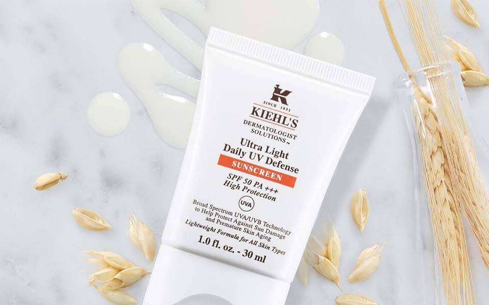 Alt-Text: Zwei Hautpflegeprodukte von Kiehl's auf einer marmorierten Oberflache, umgeben von dekorativen Elementen wie Hafer und einer Sternform.