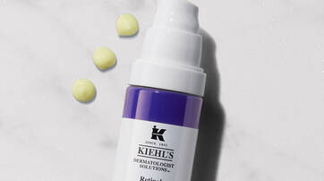 Flasche mit Kiehl's Retinol Skin-Renewing Serum, umgeben von zwei kleinen Tropfen.