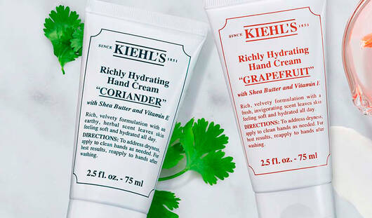 Verschiedene Kiehl's Hautpflegeprodukte auf einer marmorierten Oberflache, umgeben von frischen Zutaten wie Avocado und Krautern.