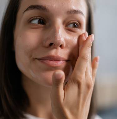 Frau verteilt Creme auf dem Gesicht