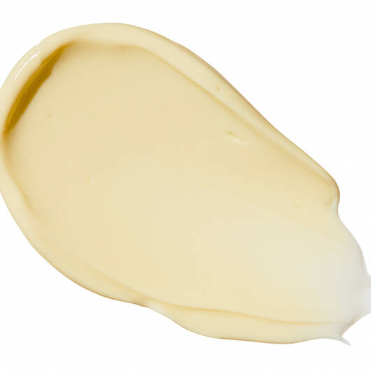 Ein cremefarbener bis hellgelber Klecks einer Creme oder Lotion mit glatter Textur, isoliert auf weißem Hintergrund.