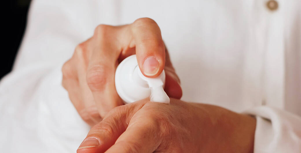 Mann tragt Bodylotion auf der Hand auf