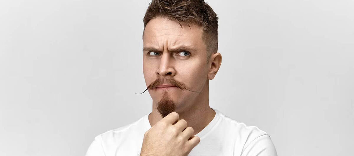 Mann mit Ziegenbart guckt lustig in die Kamera