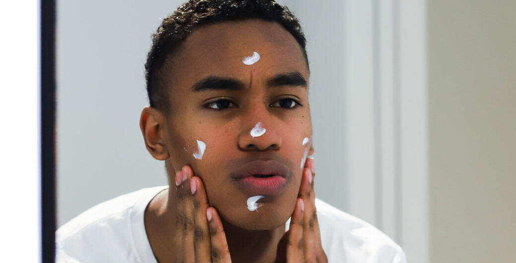 Mann cremt sich das Gesicht ein