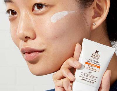 Frau mit Sonnencreme auf der Wange halt Uv Defense