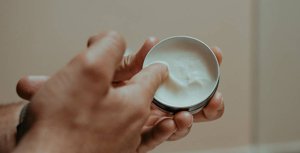 Mann tragt Bodylotion auf