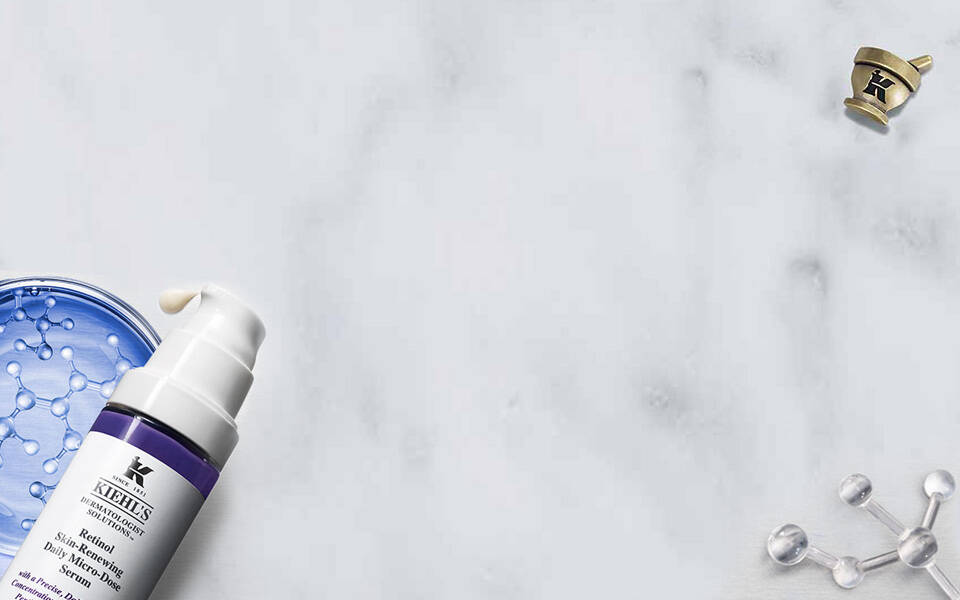 Alt-Text: Verschiedene Hautpflegeprodukte von Kiehl's auf einer marmorierten Oberflache, darunter eine blaue Gelmaske, eine Pumpflasche mit Serum und eine Flasche Creme.