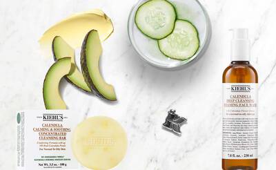 Produkte von Kiehl's: Gesichtsreinigung mit Calendula, Avocado, Gurkenscheiben und einer Seife auf Marmoroberflache.