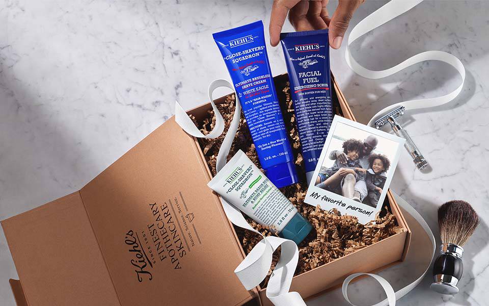 Bildbeschreibung: Eine Kiste mit verschiedenen Hautpflegeprodukten von Kiehl's, neben einem Kosmetiktaschchen mit weiteren Produkten.