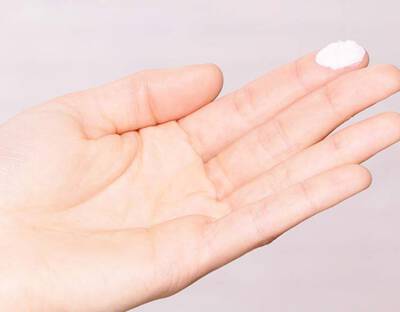 Hand mit Sonnencreme auf dem Finger