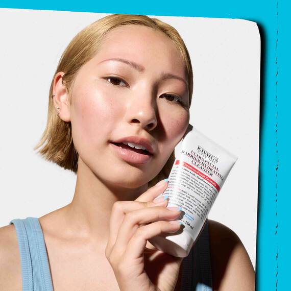 Junge Frau, die ein Kiehl's Produkt in der Hand halt