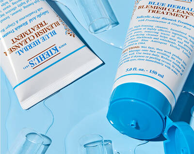 Creme et gel de traitement contre les imperfections Kiehl's sur fond bleu, accompagnes de gouttes d'eau.