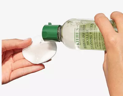 Flacon de tonique Kiehl's versant le produit sur un coton pour le nettoyage du visage.