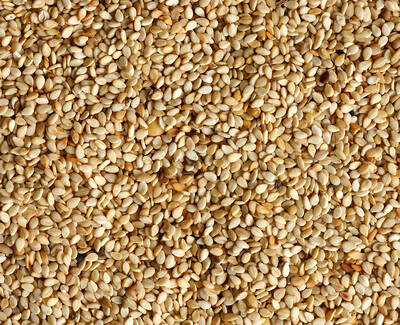 A close-up view of a textured spread of light beige sesame seeds.