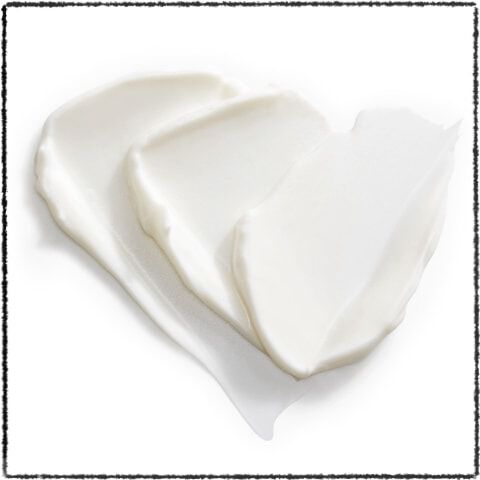 A small pile of creamy white skincare product, possibly lotion or moisturizer, with a smooth and shiny texture.