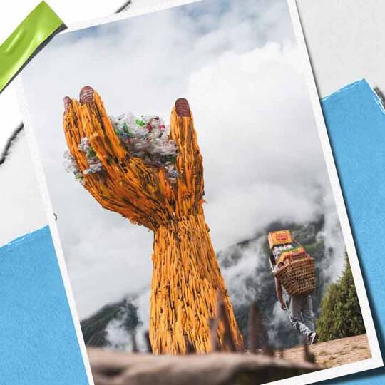 Une imposante sculpture de main en bois tient un tas de dechets, symbolisant la conscience environnementale, avec une personne transportant des marchandises a proximite.