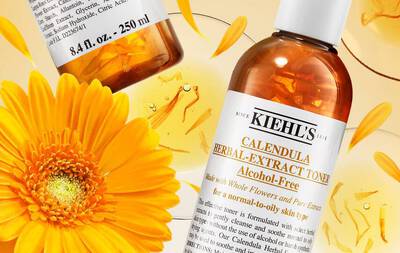 Close-up of a Kiehl's Calendula Herbal-Extract Toner bottle, surrounded by vibrant yellow calendula flowers and petals, highlighting its alcohol-free formula. The label features details about its use for normal to oily skin.
