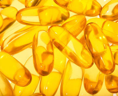 A close-up image of numerous translucent yellow capsules scattered across a bright background.