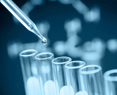 A pipette is about to drop a liquid onto a set of test tubes, with a blurred background featuring a DNA structure.
