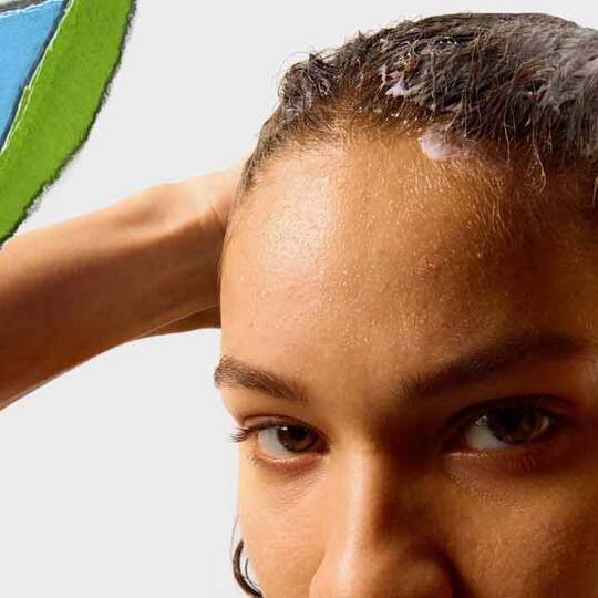 Une personne aux cheveux mouilles applique un produit capillaire, avec un fond de papier dechire colore.