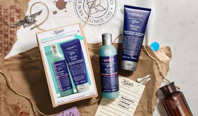A flat lay image featuring Kiehl's skincare products, including a facial fuel energizing tonic and moisturizer, presented on a textured background with packaging and decorative elements.