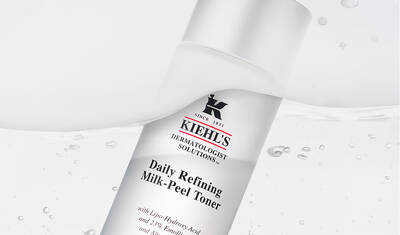 A bottle of Kiehl's Daily Refining Milk-Peel Toner, featuring a sleek design with a white background and water droplets, emphasizing its skincare properties.