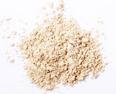 A close-up view of a scattered pile of light beige-colored powder on a white background.