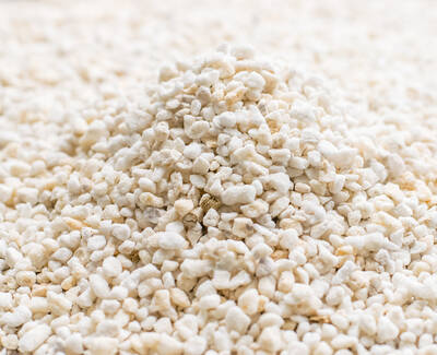 A close-up of a mound of small, irregular white pebbles or granules on a light surface.