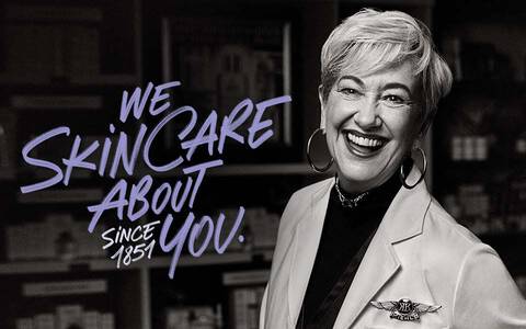 Une femme souriante se tient devant des etageres remplies de produits de soin de la peau, avec le texte « We skin care about you! » en lettres stylisees.