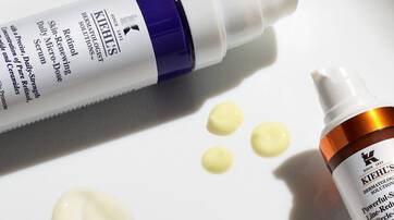 Alt-Text: Zwei Kiehl's Hautpflegeprodukte in Flaschen, daneben einige Tropfen des Inhalts auf einem weißen Untergrund.