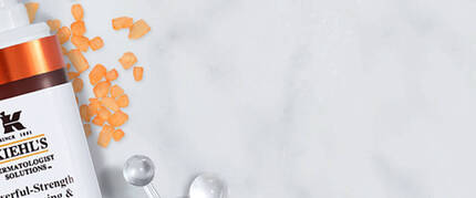 Produits de soins de la peau Kiehl's sur un fond en marbre, incluant un serum et un spray, accompagnes de fleurs de lavande.