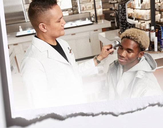 Un professionnel de la beaute appliquant un produit sur le visage d'un jeune homme, dans un environnement de soin esthetique.